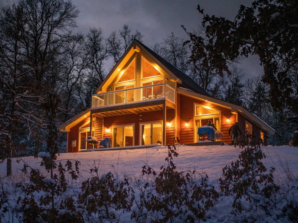 A home at night during the winter season illuminated by several outdoor fixtures