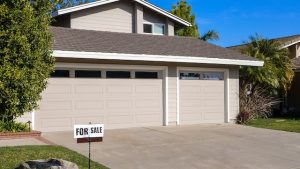 A “For Sale” sign in front of a house.